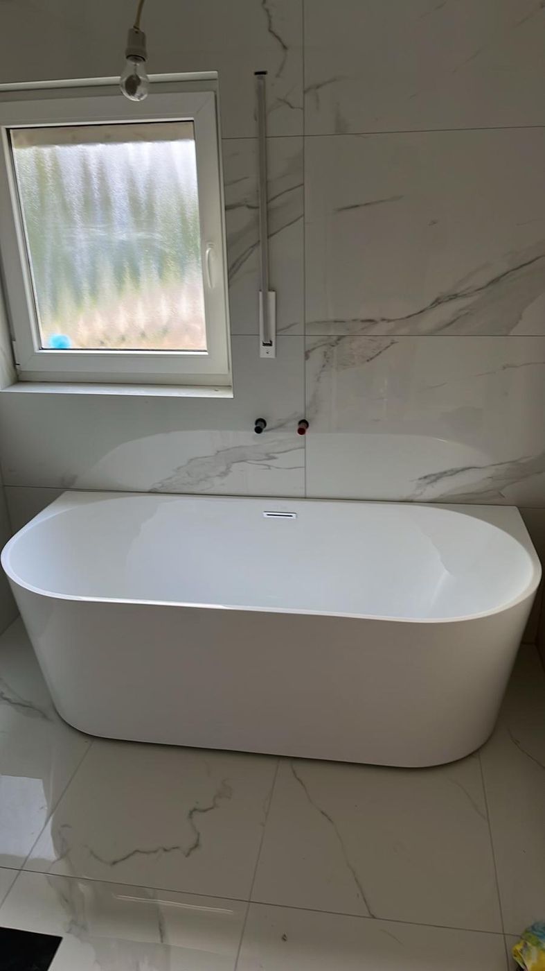 Freistehende Wanne vor Marmorwand